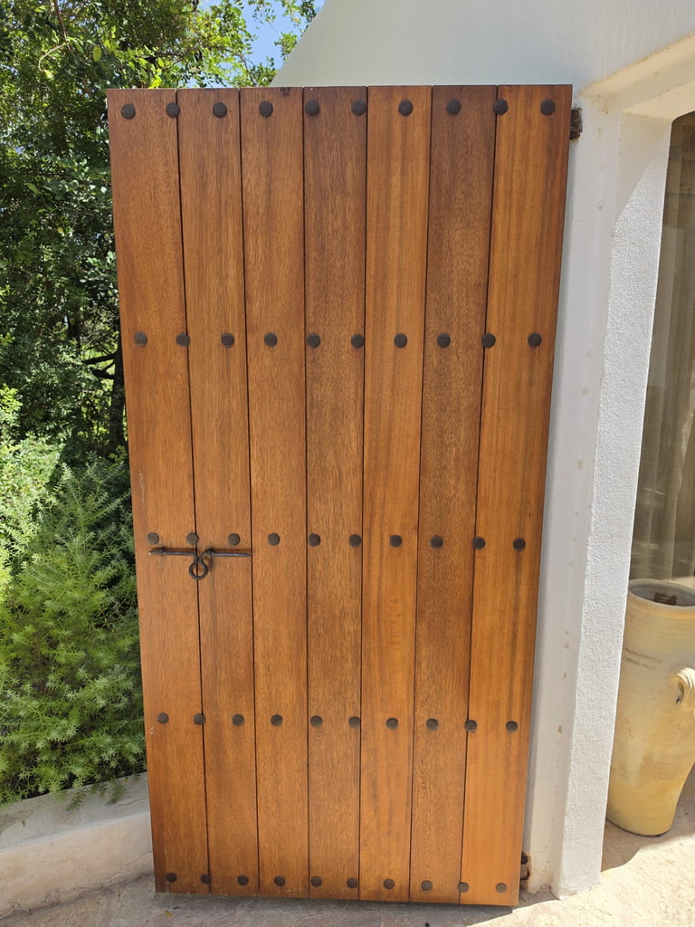 Puerta rústica exterior de madera maciza con clavos de forja, estilo ibicenco