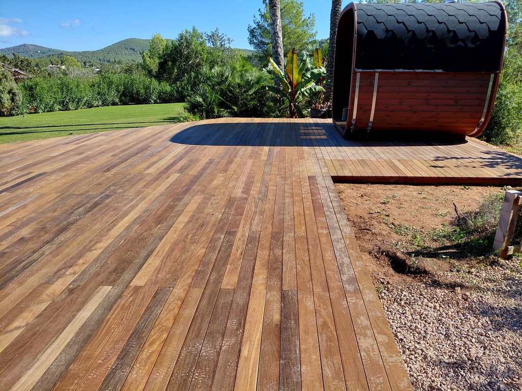 Tarima exterior de madera tropical en jardín con sauna de barril, Ibiza