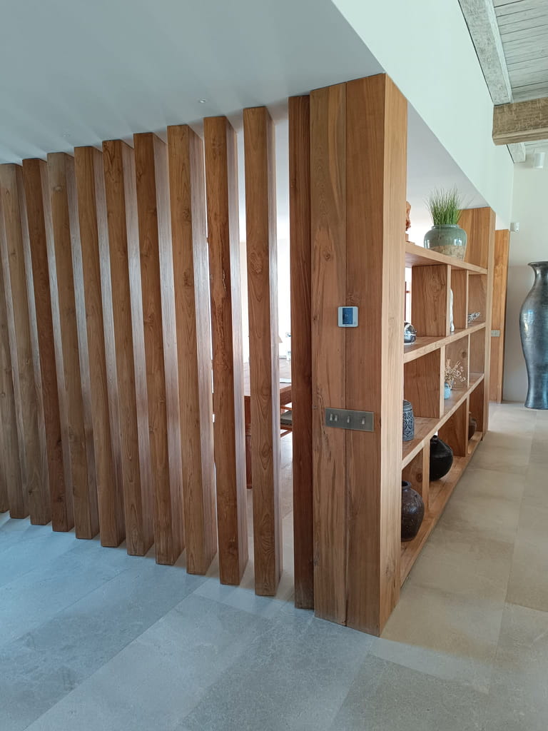 Separador de ambientes de listones verticales de madera con estantería integrada en villa de Ibiza