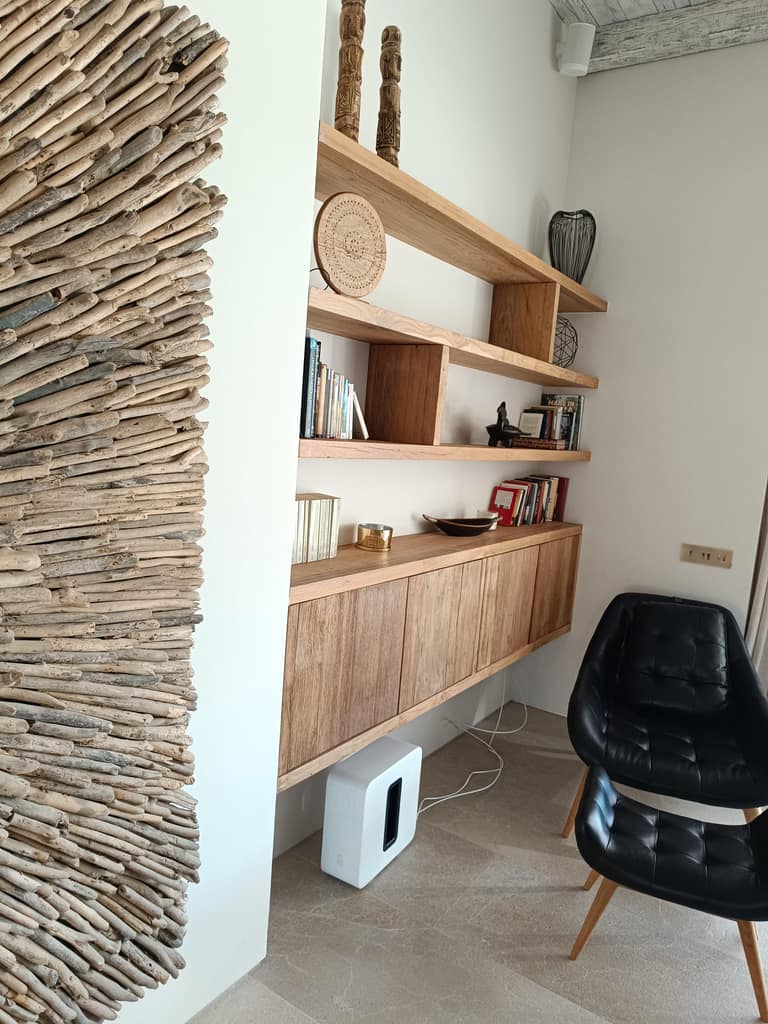 Estantes de madera maciza y mueble suspendido con puertas, hechos a medida junto a una pared de madera natural, Ibiza