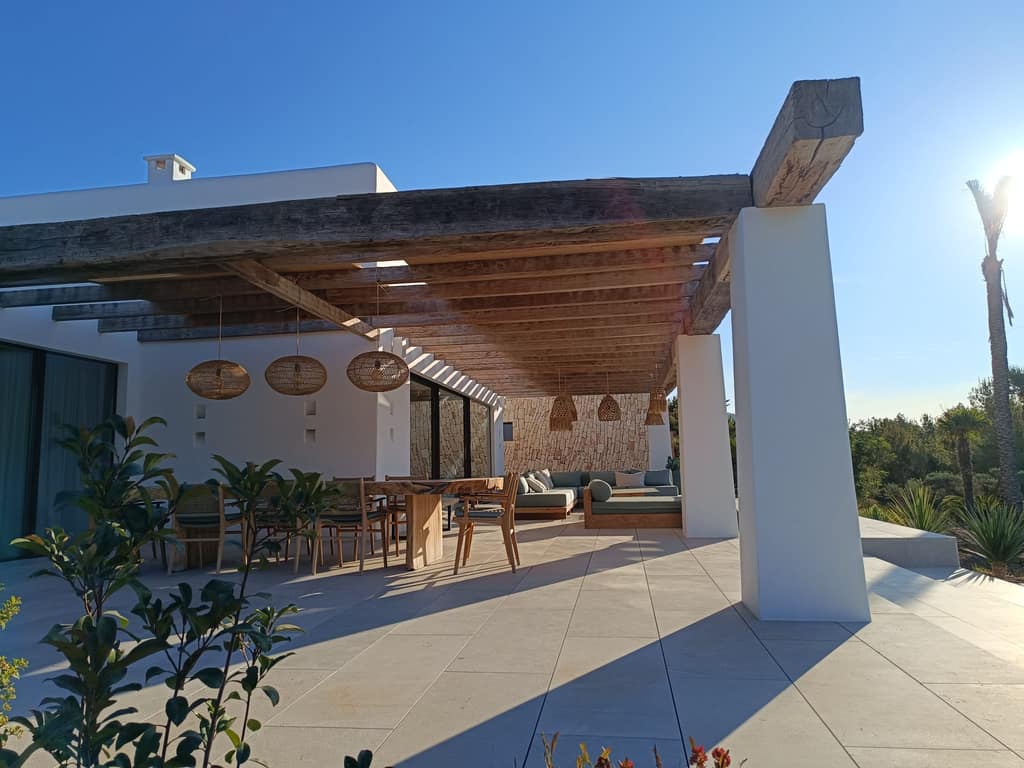 Pérgola de vigas de madera adosada a una villa, sobre comedor exterior, Ibiza