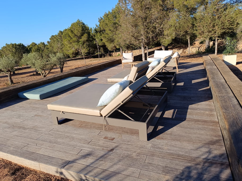 Terraza de tarima con tumbonas y banco de madera en el campo de Ibiza