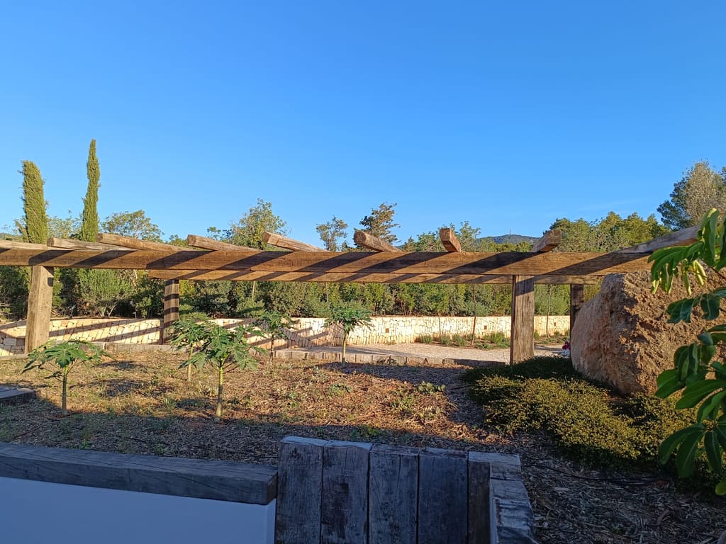 Pérgola de vigas de madera en un jardín de Ibiza