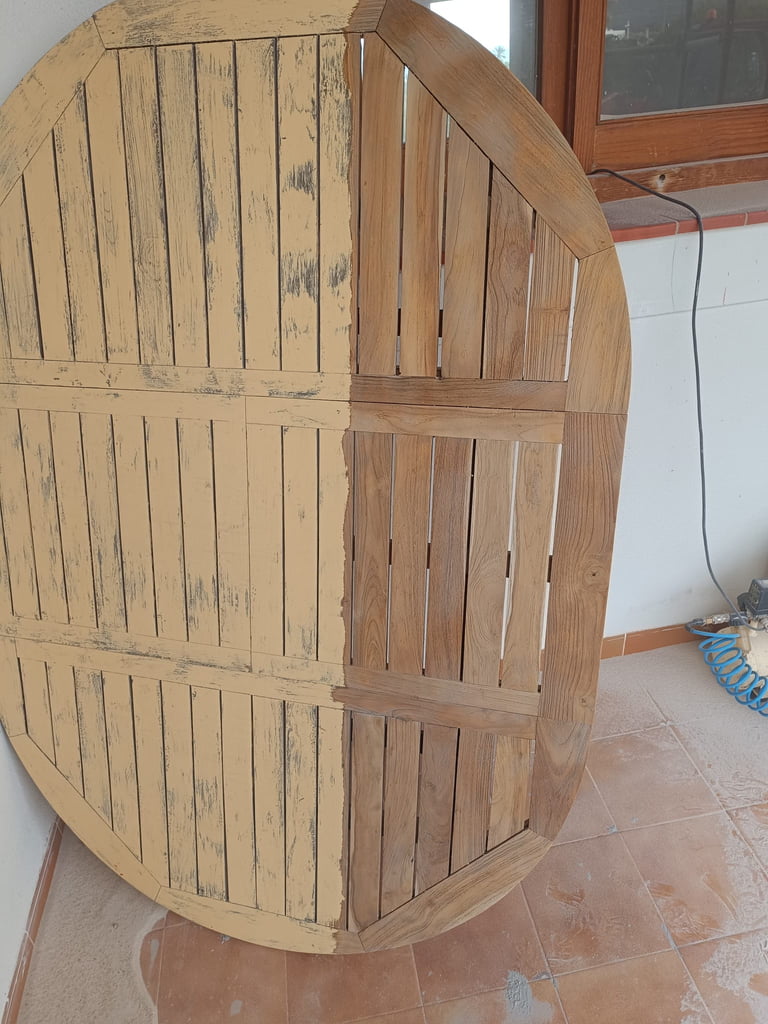 Mesa ovalada de exterior durante la restauración: la mitad lijada junto a la madera envejecida, Ibiza