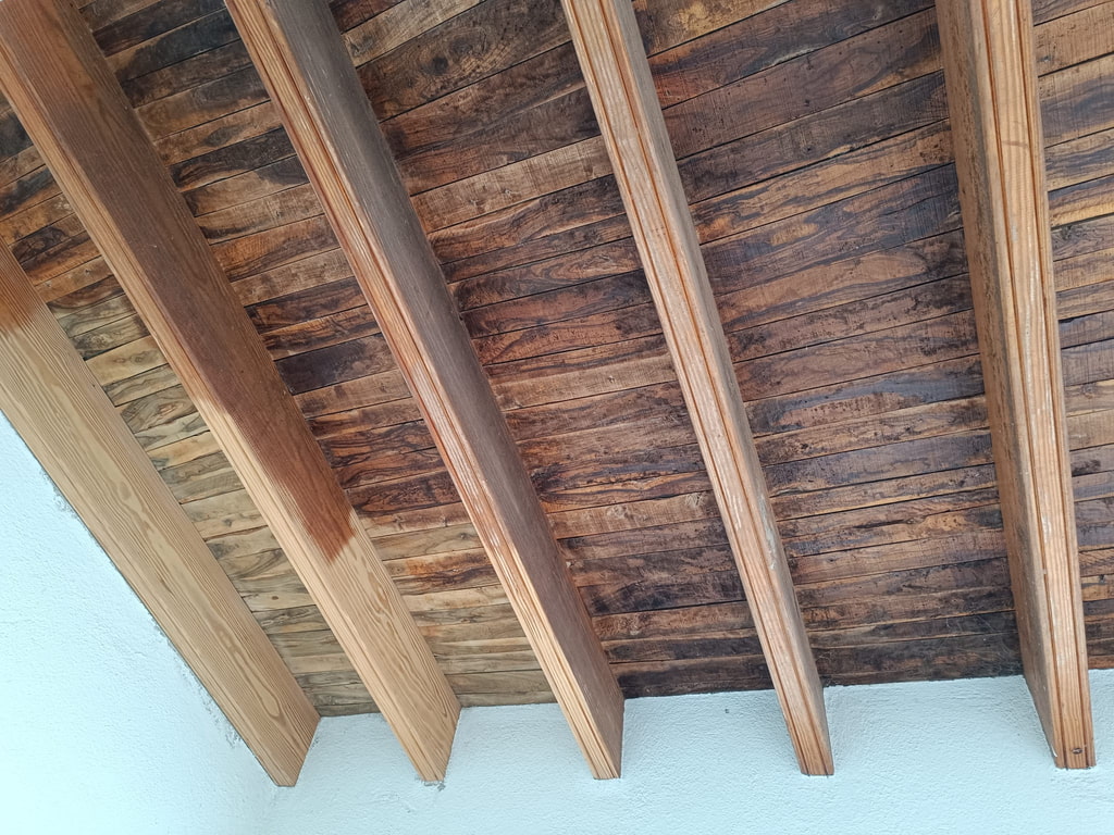 Techo de madera de un porche durante la restauración: parte tratada y parte sin tratar, Ibiza